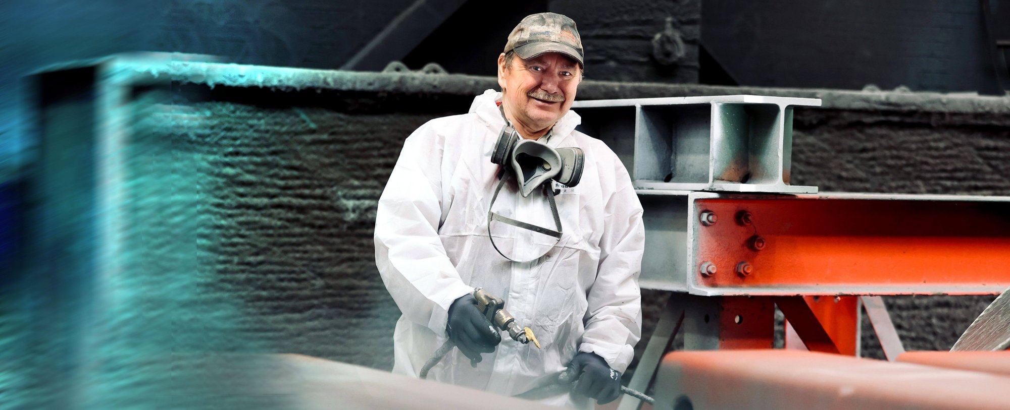 Älterer Mann in weißem Schutzanzug mit Schutzmaske und Werkzeug in der Hand