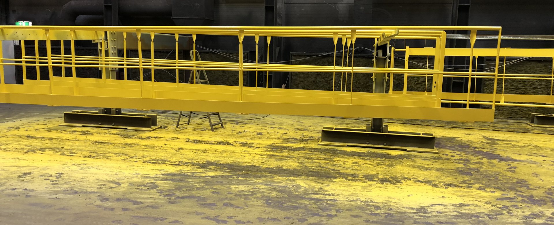 Gelb beschichtetes Stahlbauteil, frische Farbe sichtbar auf Bodenfläche